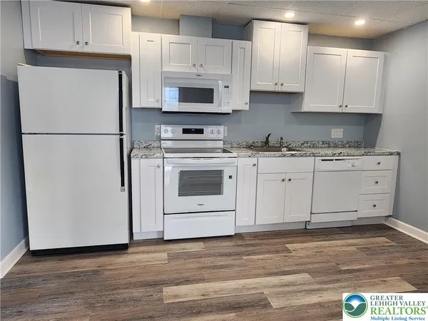 a kitchen with stainless steel appliances granite countertop a refrigerator sink and white cabinets