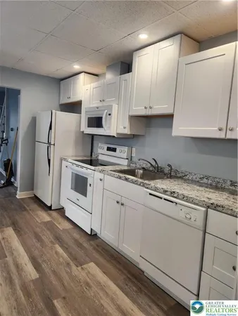 a kitchen with granite countertop white cabinets and white appliances