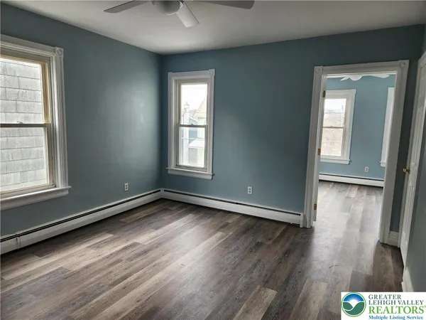 an empty room with wooden floor and windows