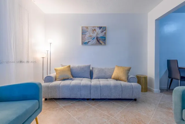 a living room with furniture a couch and a lamp on the dresser
