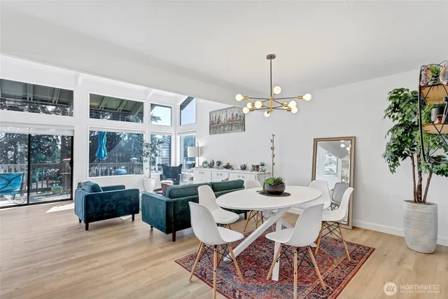 a dining room with wooden floor a chandelier a glass table and chairs