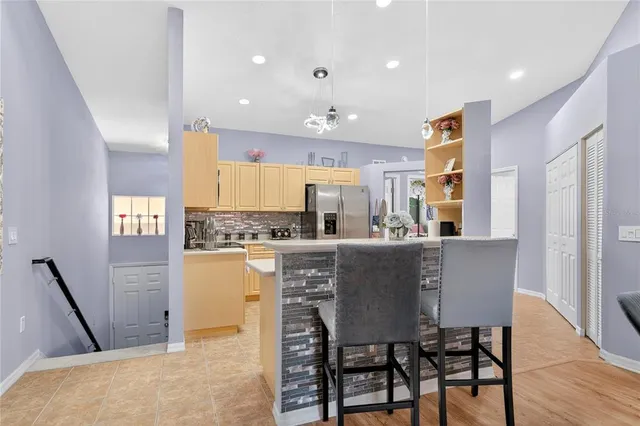a kitchen with stainless steel appliances granite countertop a table chairs sink refrigerator and cabinets