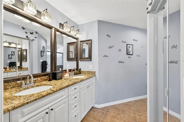 a bathroom with a granite countertop double vanity sinks and a mirror