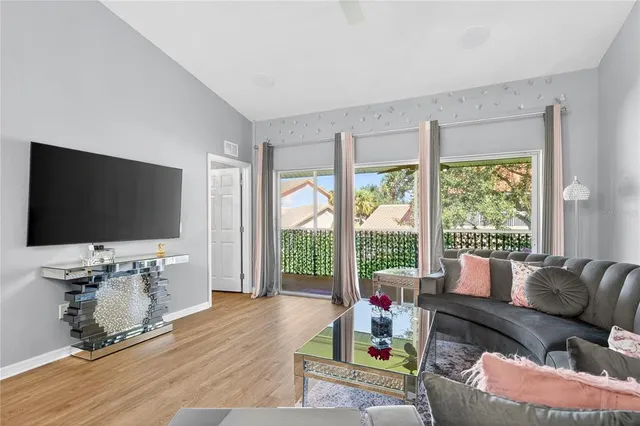 a living room with furniture a flat screen tv and floor to ceiling window