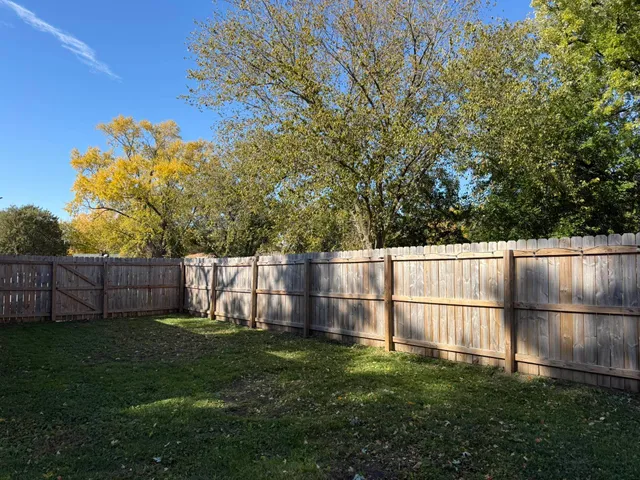a view of a backyard with a large tree and wooden fence