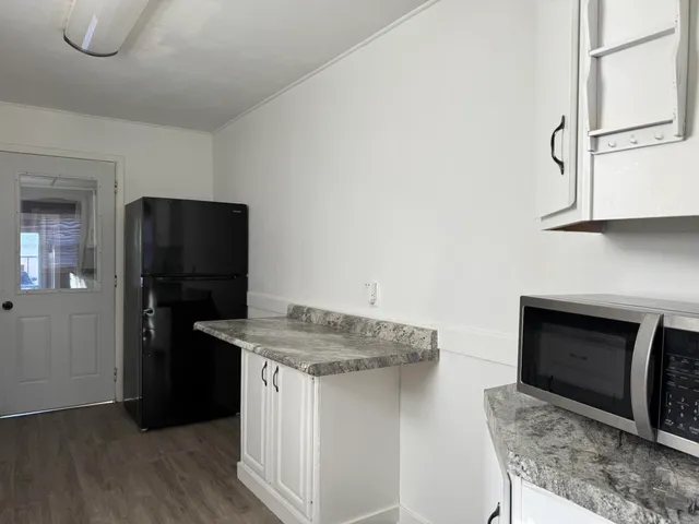 a kitchen with stainless steel appliances granite countertop a refrigerator a stove and a sink with wooden floor