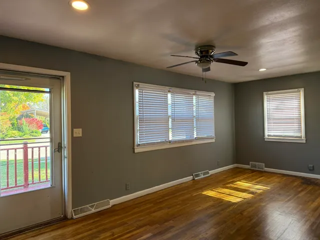 a view of empty room with wooden floor and fan