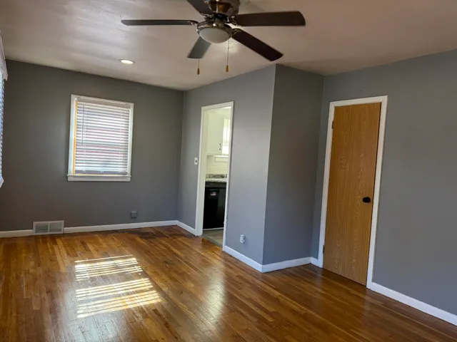 a view of empty room with wooden floor and fan