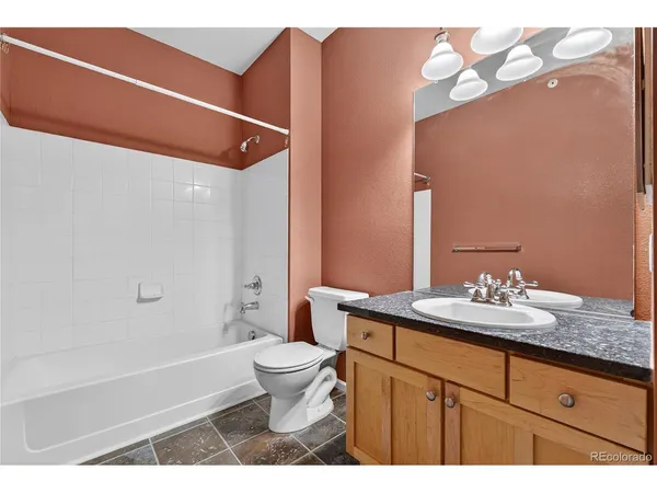 a bathroom with a granite countertop sink a toilet a mirror and bathtub