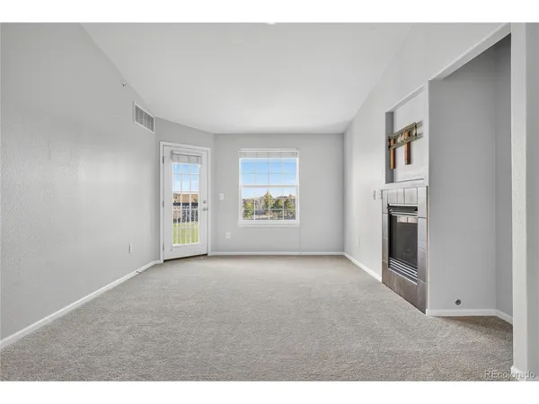 a view of an empty room with a fireplace and a window