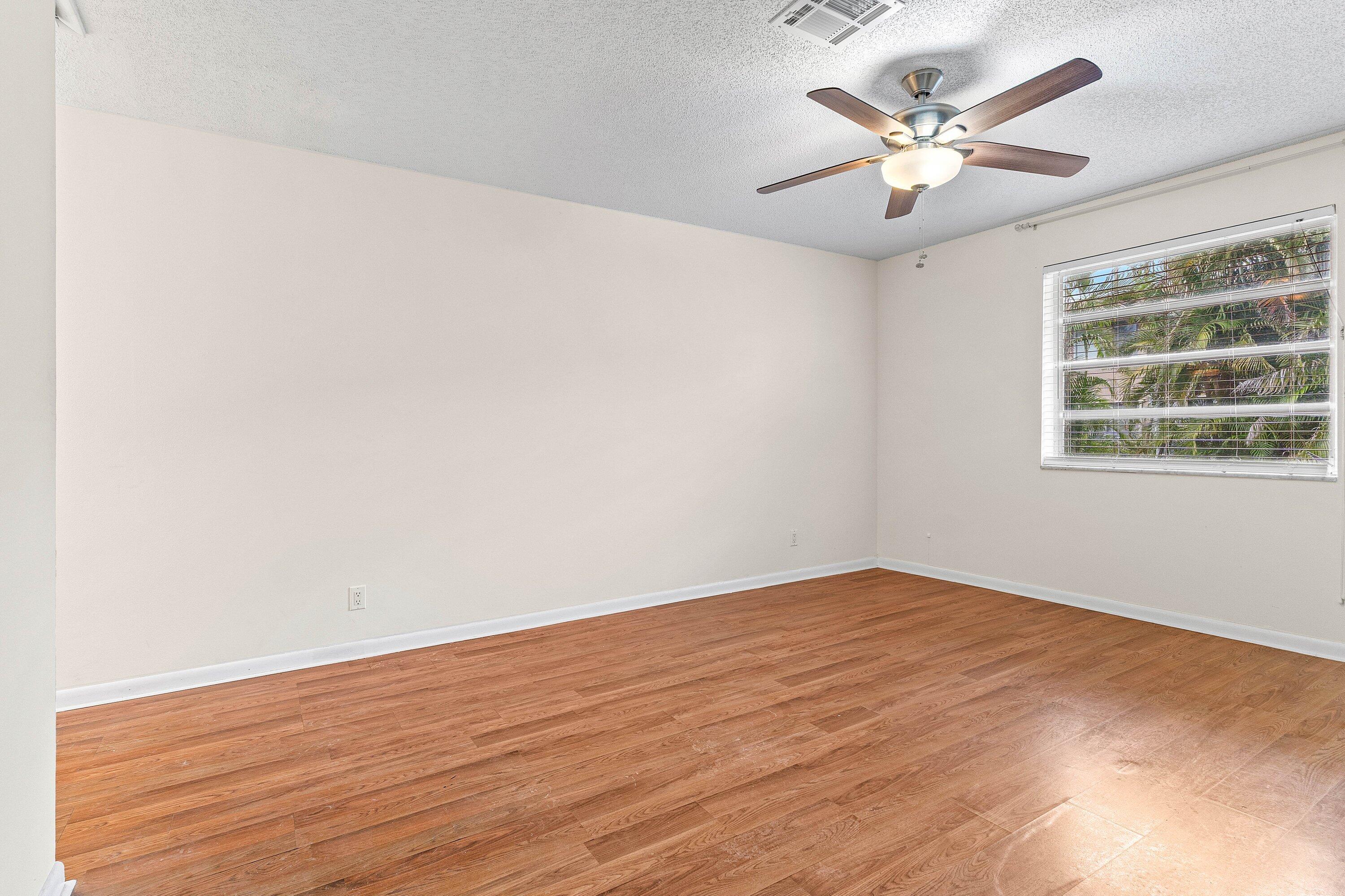 13899 Via Aurora, Unit C Delray Beach, FL 33484 - Photo 22 of 39 an empty room with wooden floor and windows