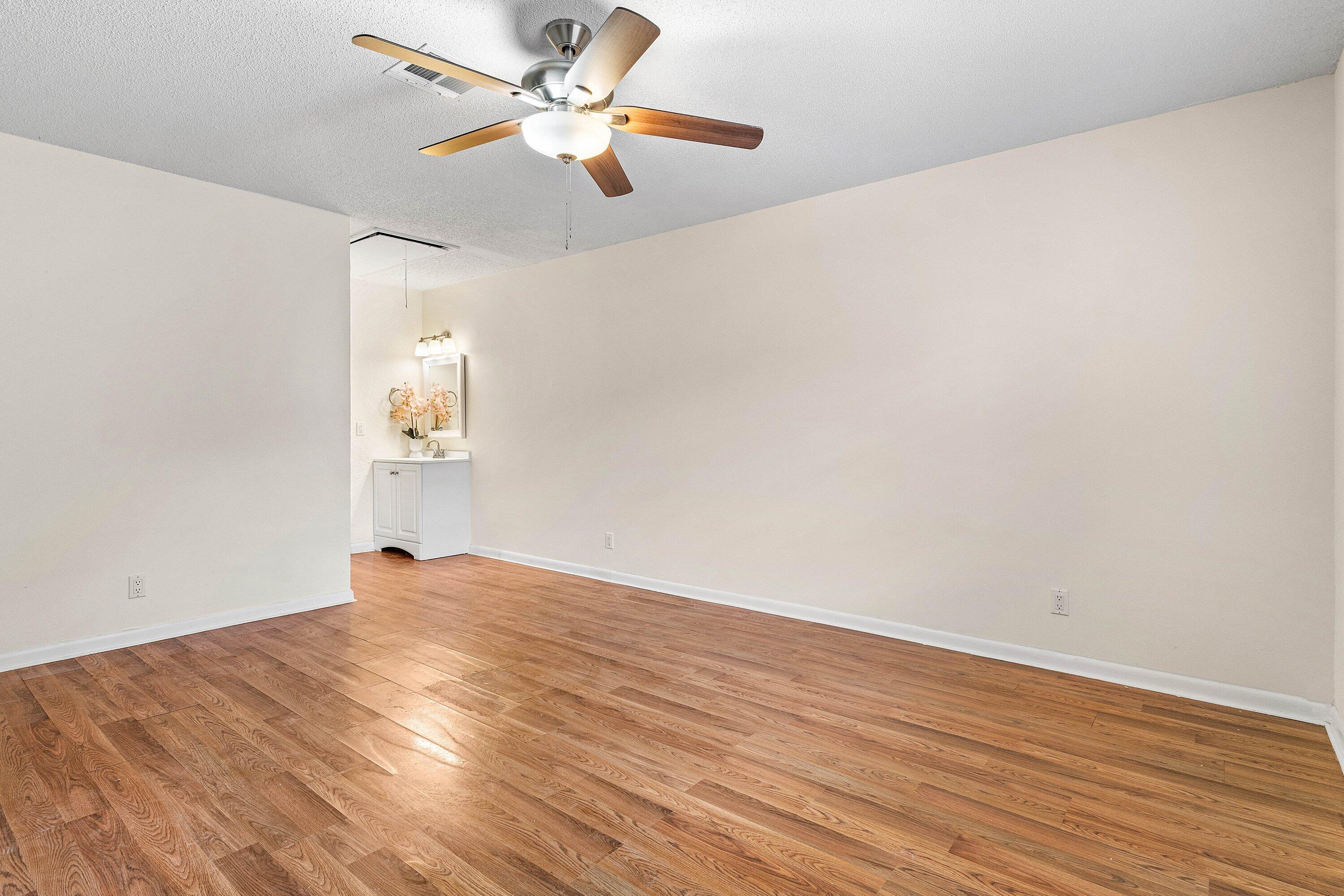 13899 Via Aurora, Unit C Delray Beach, FL 33484 - Photo 24 of 39 an empty room with wooden floor fan and windows