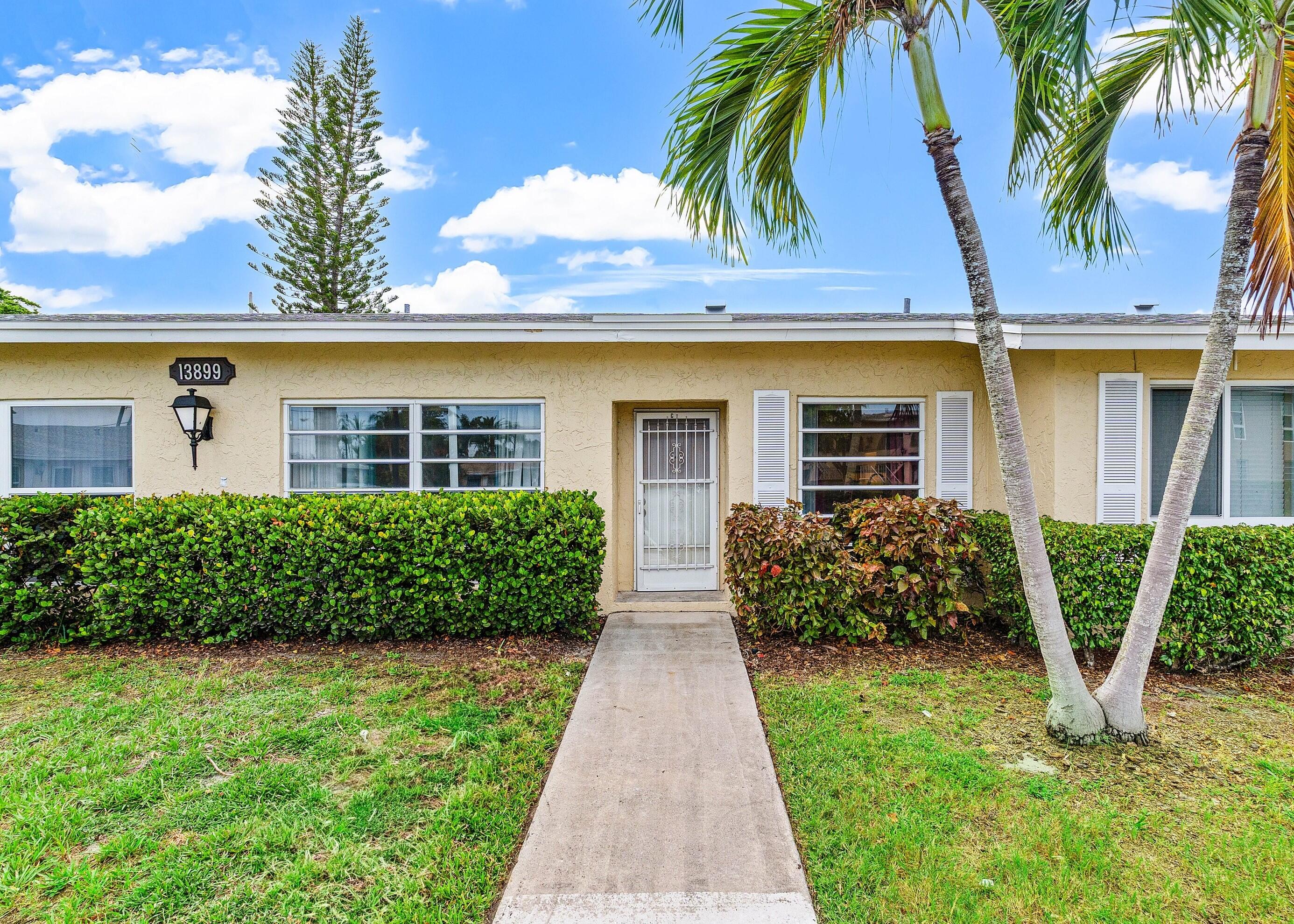 13899 Via Aurora, Unit C Delray Beach, FL 33484 - Photo 32 of 39 a front view of a house with a garden