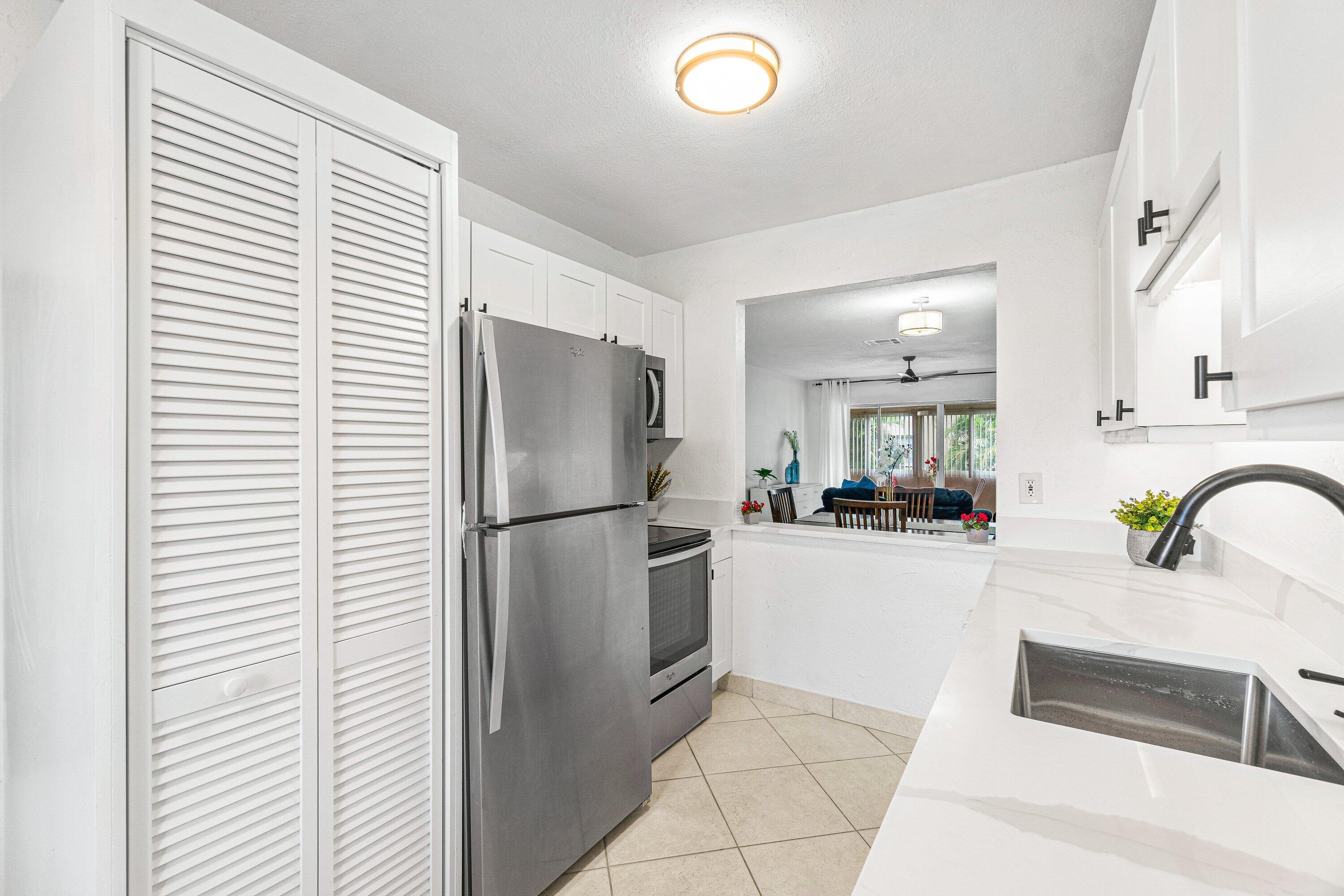 13899 Via Aurora, Unit C Delray Beach, FL 33484 - Photo 5 of 39 a kitchen with a refrigerator and a sink