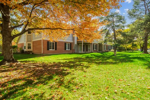 a view of a house with a big yard and large trees