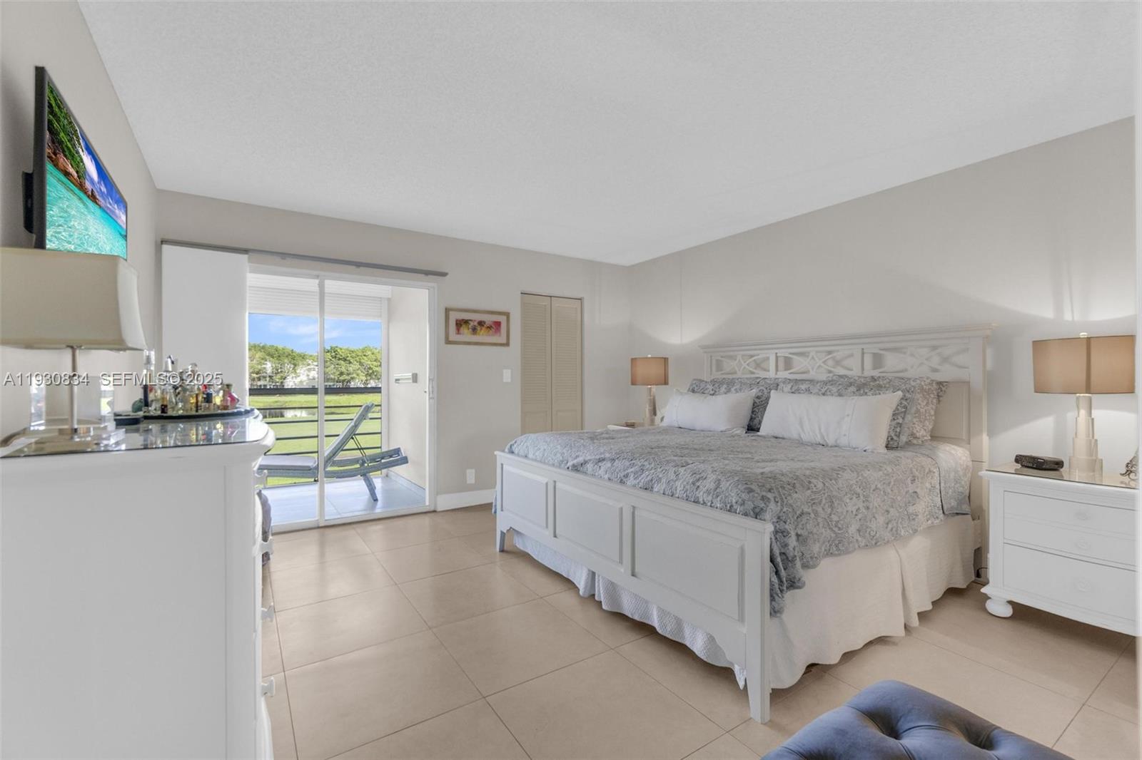 4402 Martinique Court, Unit K2 Coconut Creek, FL 33066 - Photo 16 of 38 a bedroom with a bed lamp and a large window