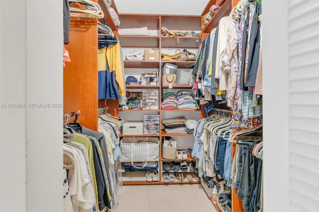 a view of walk in closet with clothes and shoes