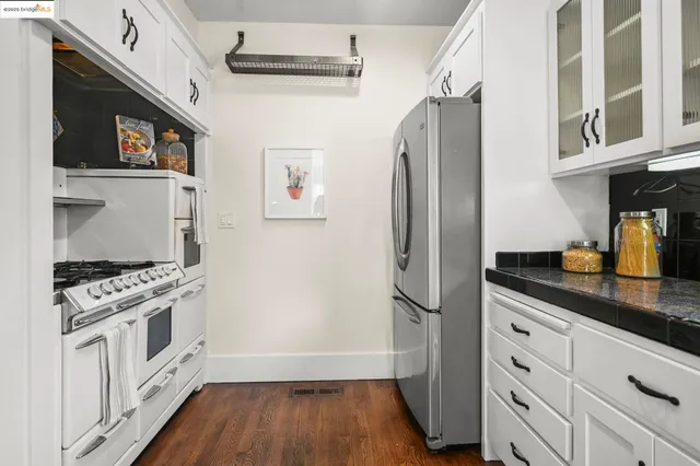 a kitchen with stainless steel appliances granite countertop a refrigerator a stove and a sink with wooden floor