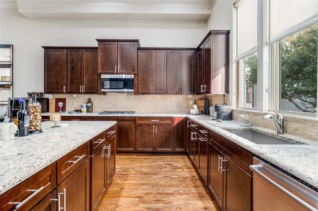 a kitchen with stainless steel appliances granite countertop a sink a stove a counter space and cabinets