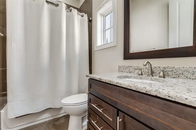 a bathroom with a granite countertop sink toilet and mirror