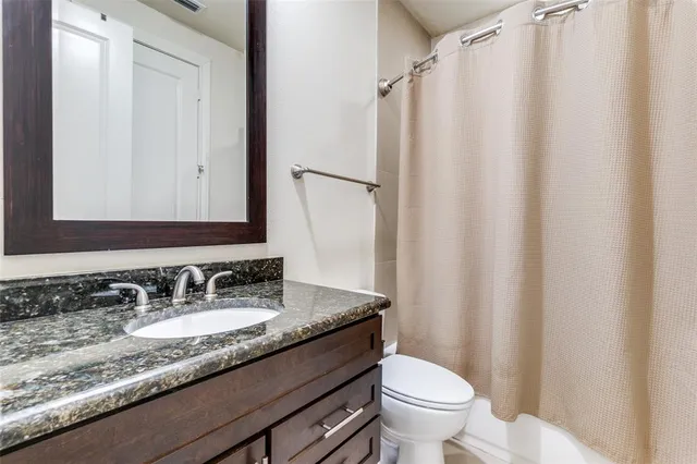 a bathroom with a granite countertop sink toilet and a mirror