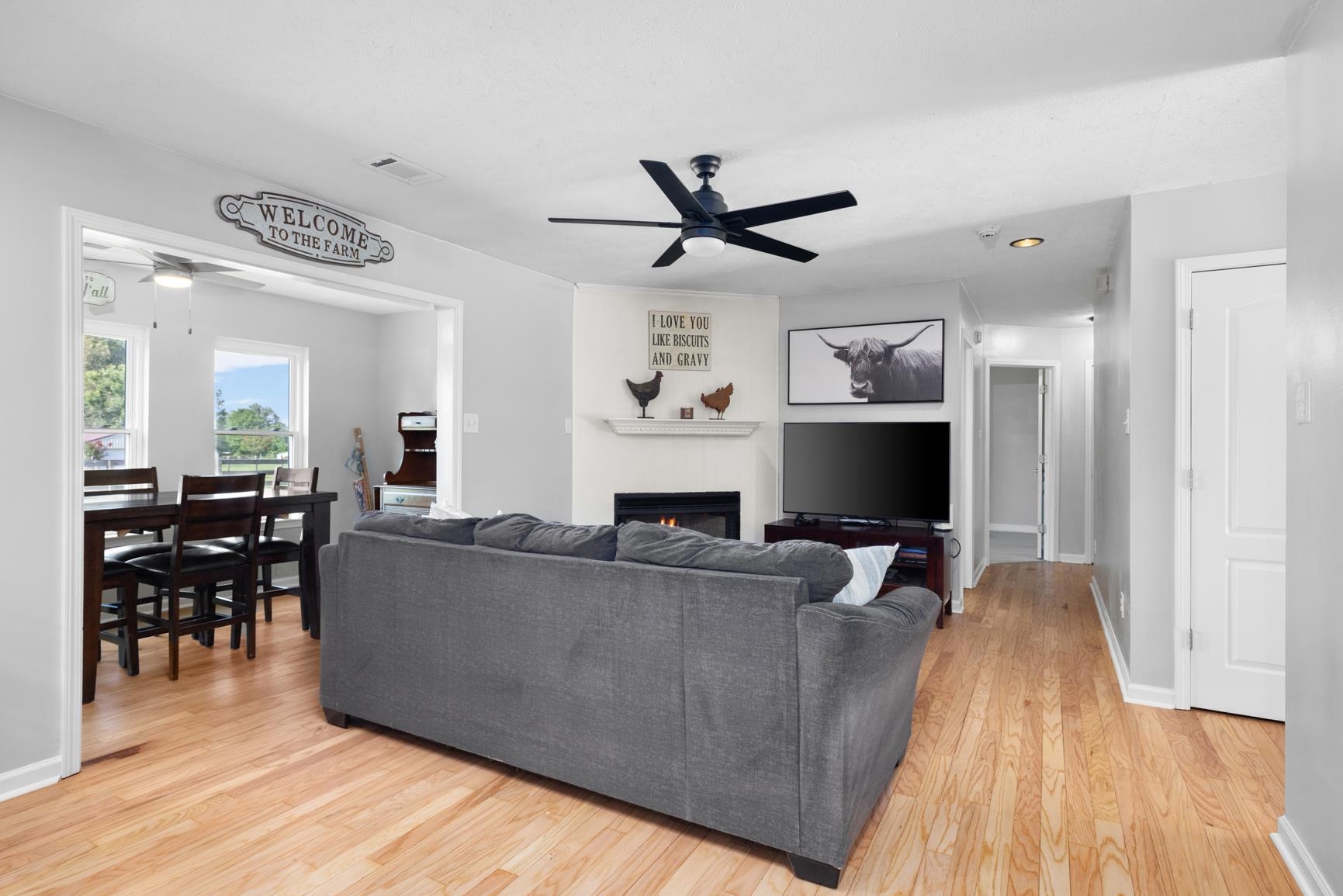 2640 Brighton-Clopton Road Brighton, TN 38011 - Photo 34 of 36 Living area featuring ceiling fan, a warm lit fireplace, and light wood-type flooring