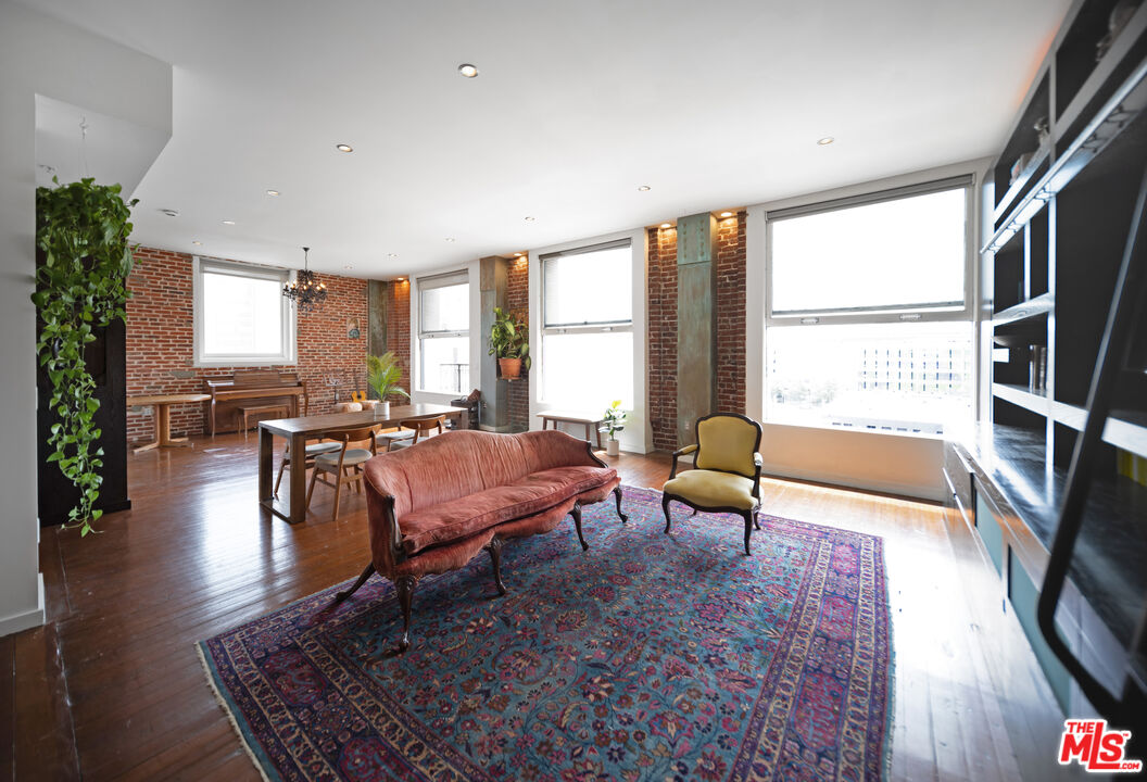 a living room with furniture large window and wooden floor