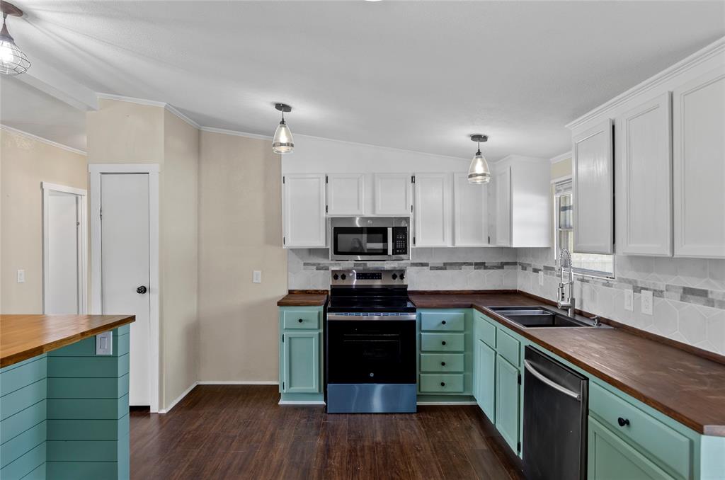 401 Barker Street Bowie, TX 76230 - Photo 11 of 24 a kitchen with granite countertop a stove top oven a sink dishwasher and a refrigerator with wooden floor