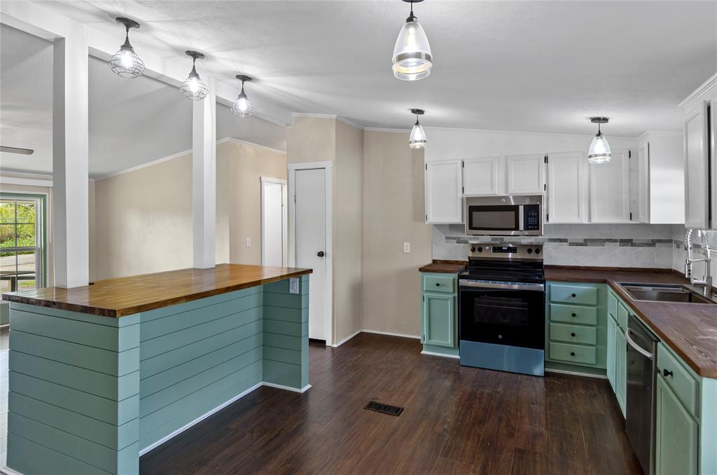 401 Barker Street Bowie, TX 76230 - Photo 13 of 24 a kitchen with stainless steel appliances a stove refrigerator and microwave