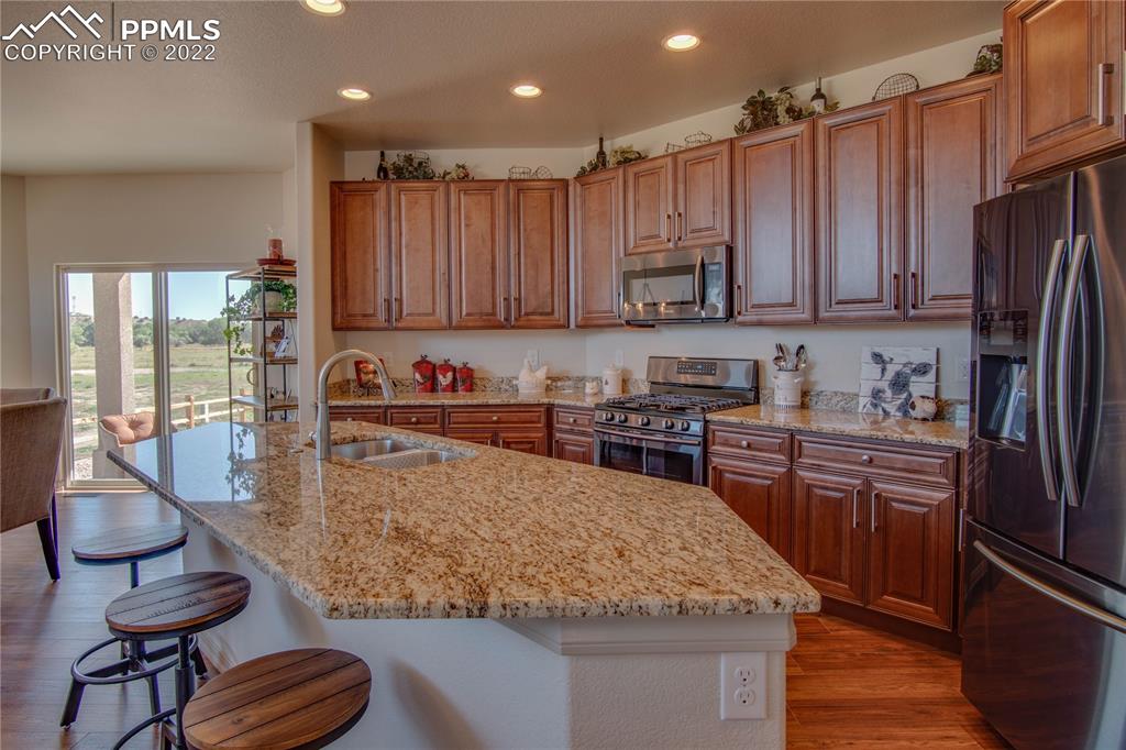 124 Rocchio Drive Florence, CO 81226 - Photo 2 of 34 a kitchen with kitchen island granite countertop wooden cabinets a stove a sink and a refrigerator