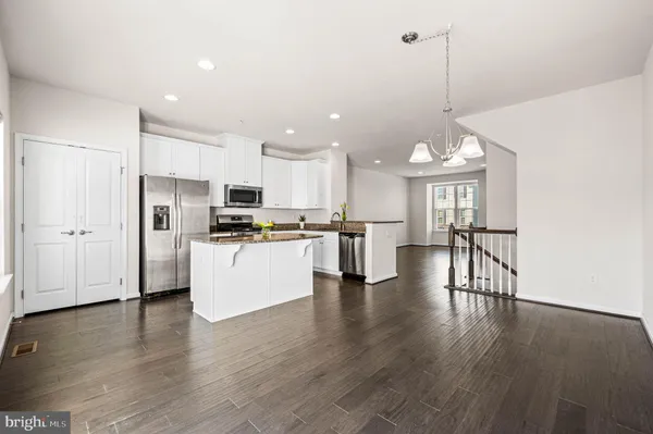 a view of kitchen with stainless steel appliances granite countertop a stove top oven a refrigerator a sink and a wooden floor