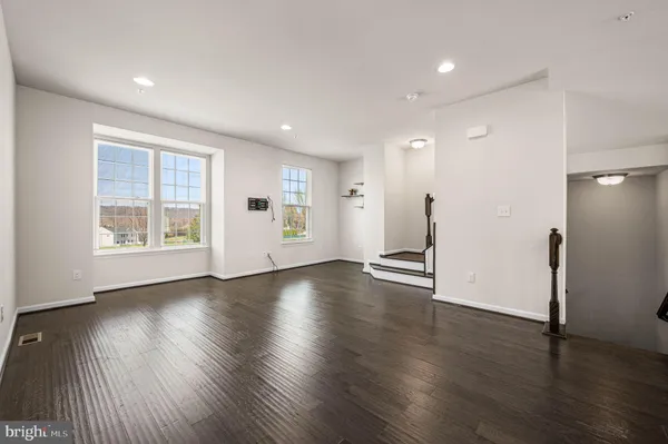 a view of an empty room with wooden floor and windows