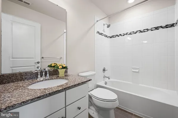 a bathroom with a granite countertop sink a toilet a mirror and shower