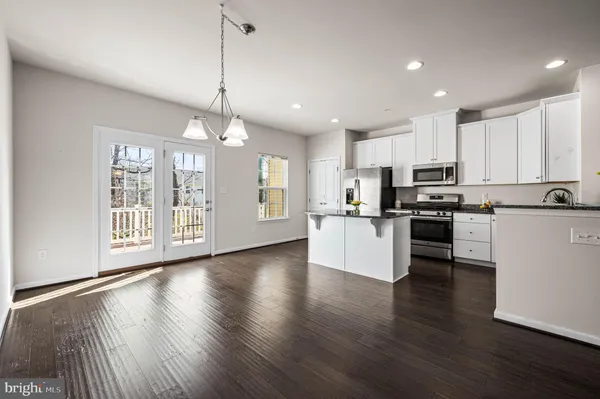 a kitchen with stainless steel appliances granite countertop a refrigerator a stove top oven a sink with island and white cabinets