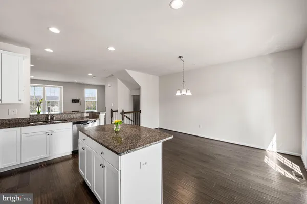 a kitchen with granite countertop kitchen island wooden floor center island and stainless steel appliances