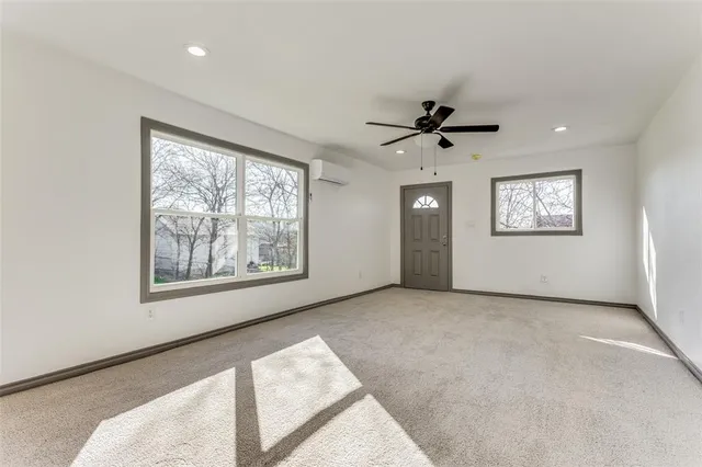 an empty room with chandelier fan and windows