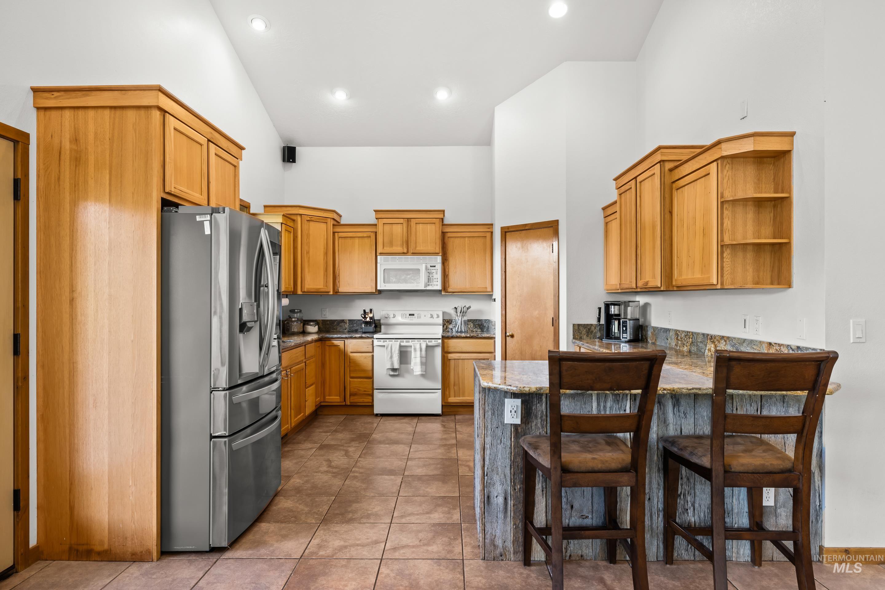 92 Cruickshank Road Horseshoe Bend, ID 83629 - Photo 17 of 50 Kitchen featuring vaulted ceilings, recessed lighting, wood cabinetry, granite-finish countertops, and an island with bar seating