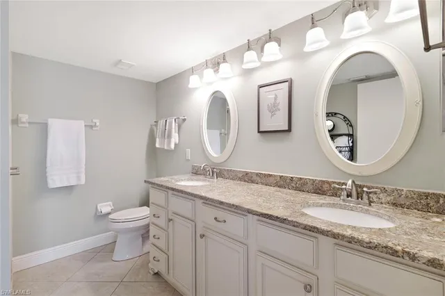 a bathroom with a granite countertop toilet a sink and a mirror
