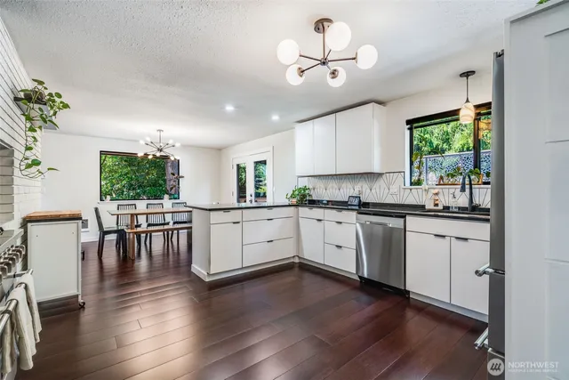 a kitchen with stainless steel appliances granite countertop wooden floors and white cabinets
