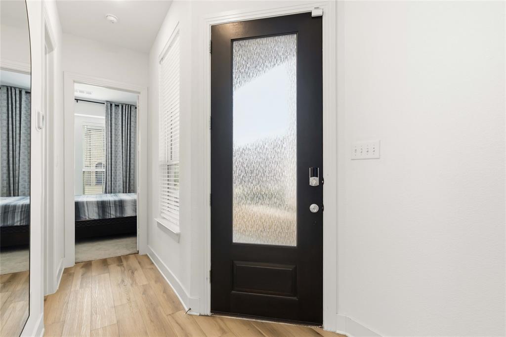 1128 Queensdown Way Forney, TX 75126 - Photo 5 of 30 Entryway featuring a dark paneled door with a textured glass insert, wood-finish flooring, white baseboards, and a window with horizontal blinds