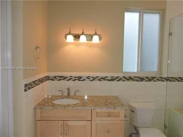 a bathroom with a granite countertop sink a mirror and shower