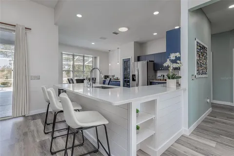 a kitchen with stainless steel appliances granite countertop a table chairs sink and cabinets