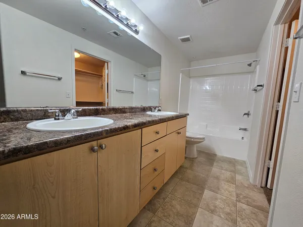 a spacious bathroom with a granite countertop sink a mirror and a toilet
