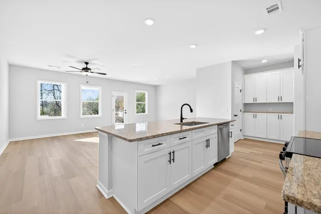 a large kitchen with stainless steel appliances granite countertop a lot of counter space and wooden floors