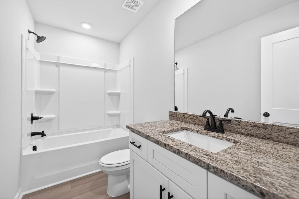 578 Madison Street, Unit 100 Commerce, GA 30529 - Photo 23 of 37 a bathroom with a granite countertop sink toilet and shower