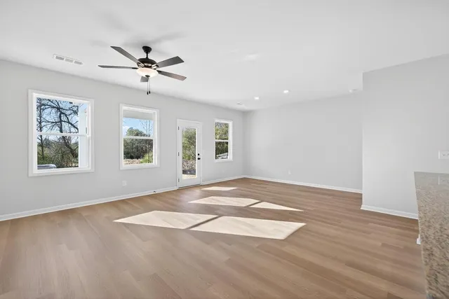 a view of an empty room with window and wooden floor