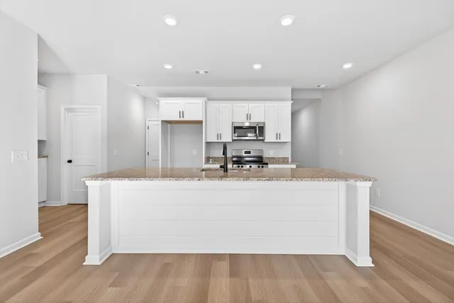 a view of kitchen with stainless steel appliances granite countertop cabinets and wooden floor