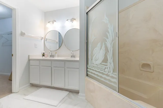 a bathroom with a double vanity sink mirror and bathtub