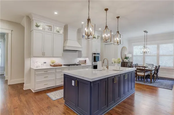 a large kitchen with kitchen island a island a sink a stove and a wooden floors