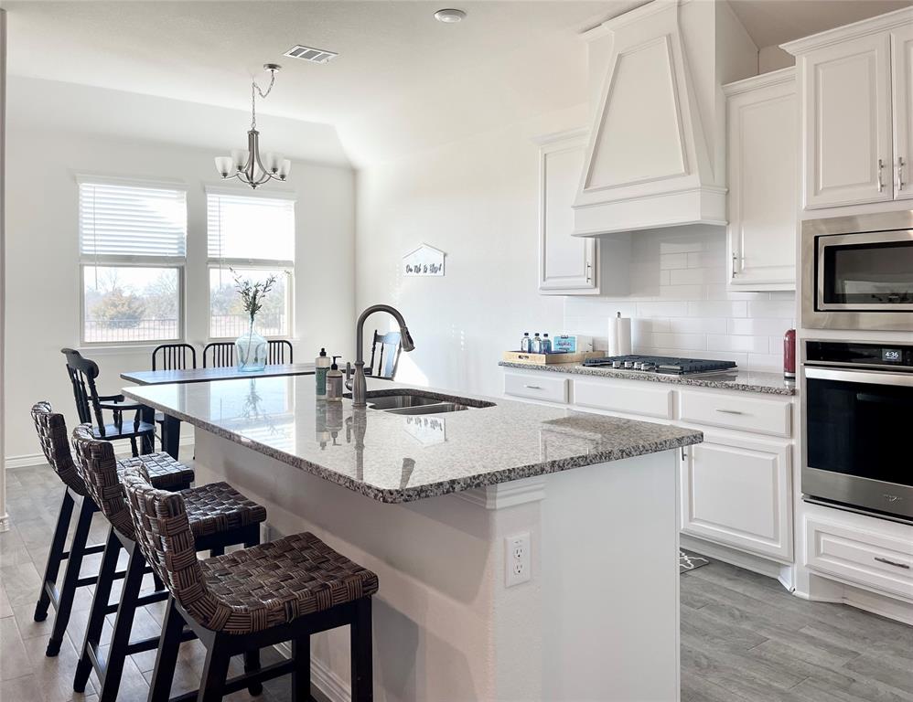 1041 Sublime Drive Forney, TX 75126 - Photo 11 of 26 a kitchen with kitchen island granite countertop a sink a stove and chairs
